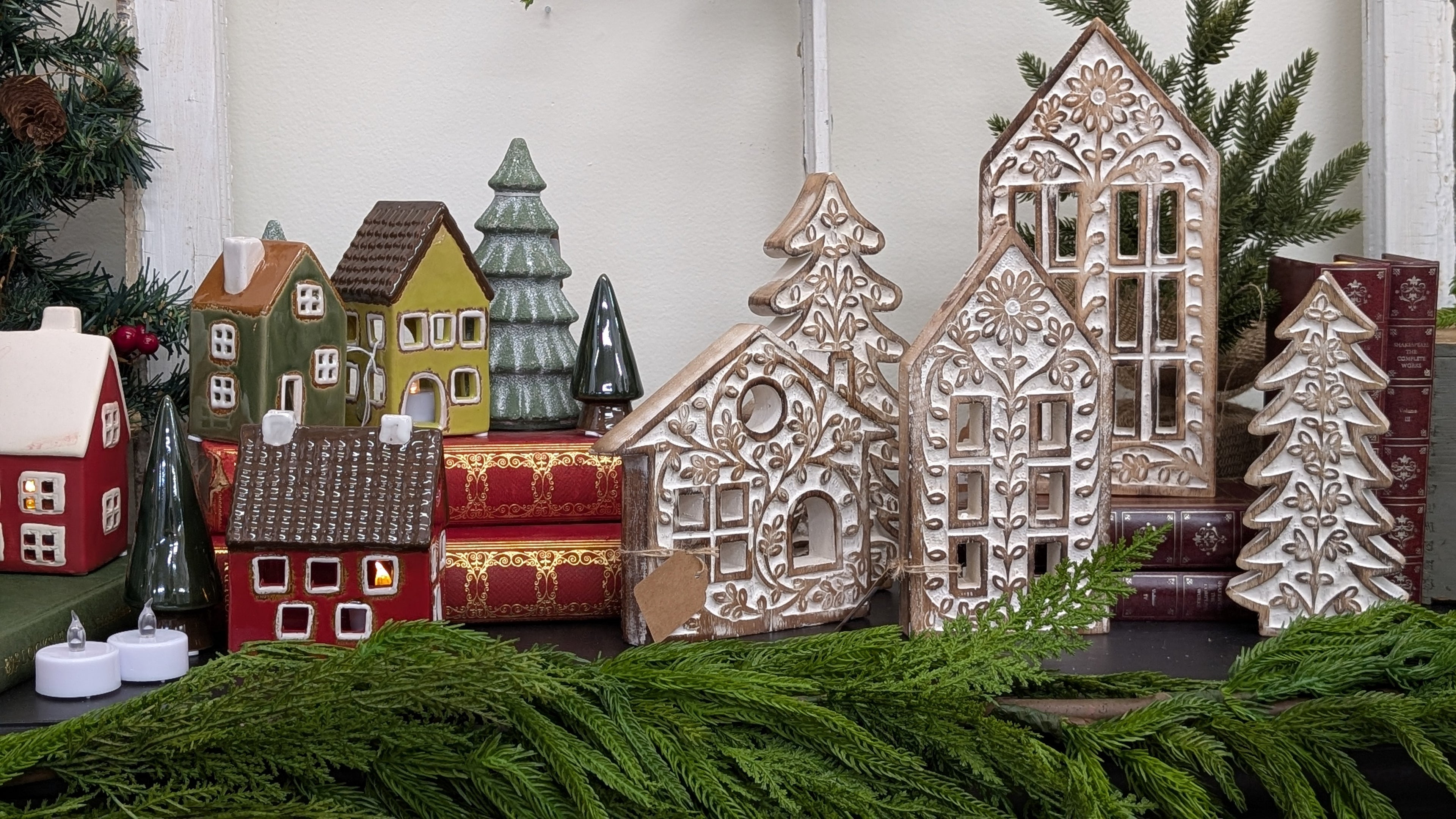 Decorative gingerbread houses and trees on a table with greenery.